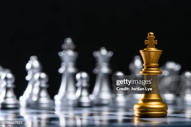 gold king chess piece facing a team of silver chess pieces - gold chess king stock pictures, royalty-free photos & images