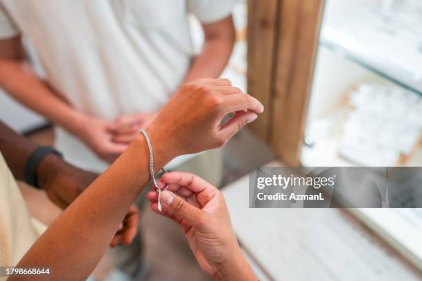 hispanic female trying a bracelet at jewelry store - bracelet stock pictures, royalty-free photos & images
