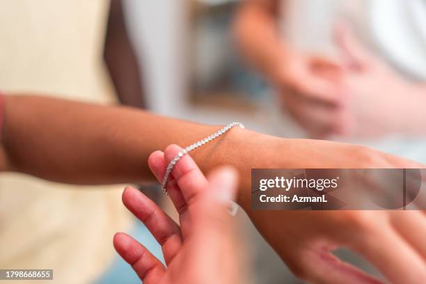 hispanic female trying a bracelet at jewelry store - bracelet stock pictures, royalty-free photos & images