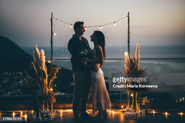 bride and groom stand near the wedding arch at night with lights, silhouettes of the newlyweds. - destination wedding imagens e fotografias de stock