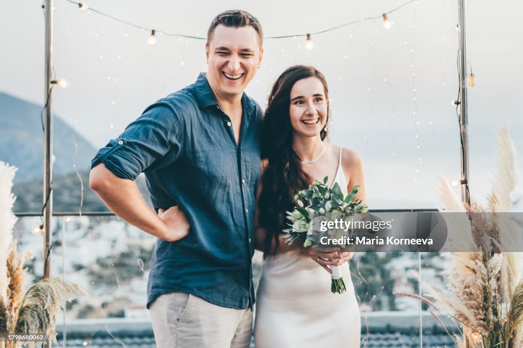 Bride and groom stand near the wedding arch.