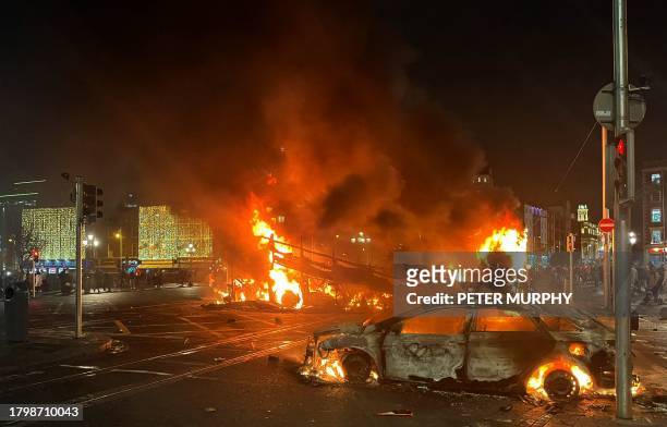Flames rise from the car and a bus, set alight at the junction of Bachelors Walk and the O'Connell Bridge, in Dublin on November 23 as people took to...