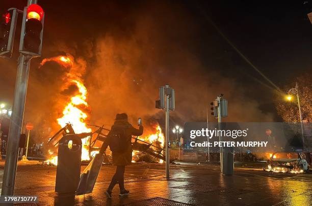 Flames rise from the car and a bus, set alight at the junction of Bachelors Walk and the O'Connell Bridge, in Dublin on November 23 as people took to...