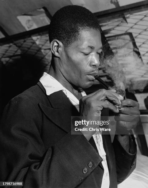 Jamaican RH Smith lighting his pipe after his arrival at the Clapham Shelter in London, England, 1st July 1948. Smith is among many who had travelled...