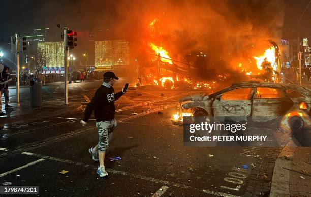 Flames rise from a car and a bus, set alight at the junction of Bachelors Walk and the O'Connell Bridge, in Dublin on November 23 as people took to...