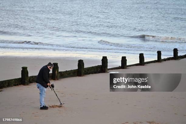 Detectorist uses a metal detector on the beach at dusk on November 15, 2023 in Frinton-on-Sea, United Kingdom.