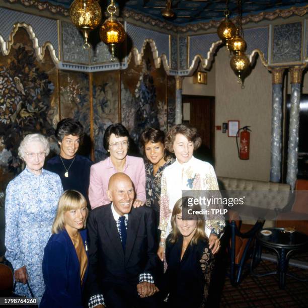 Portrait of fashion designer Ted Tinling as he poses with group of tennis players to celebrate of his 50th anniversary of designing for the Wimbledon...