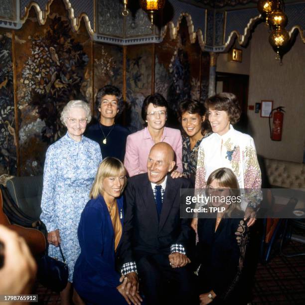 Portrait of fashion designer Ted Tinling as he poses with group of tennis players at a celebration of his 50th anniversary of designing for the...