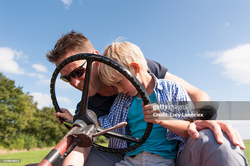 Father teaching his son to drive a tractor