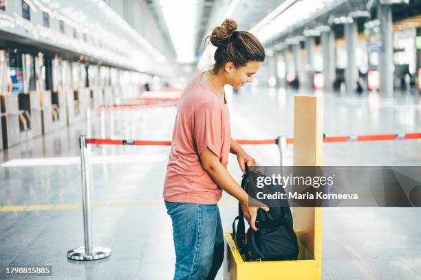 woman checking size of her carry-on luggage at airport. - luggage stock pictures, royalty-free photos & images