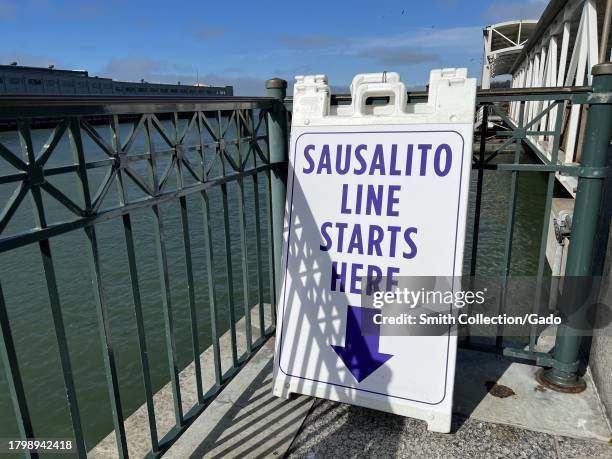 Sign indicating the beginning of the Sausalito ferry line at Harry Bridges Plaza, with a glimpse of the Port of San Francisco in the background, San...