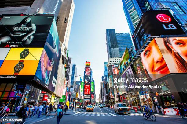 crowded times square with multiple ads on a sunny day with clear blue sky, wide angle view, new york, usa - broadway manhattan stockfoto's en -beelden