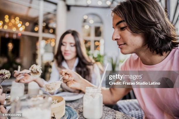 joven comiendo comida china en un restaurante - raviolis chinos fotografías e imágenes de stock