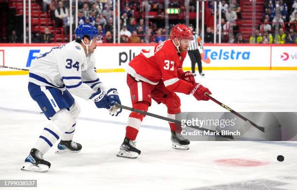Auston Matthews of the Toronto Maple Leafs and J.T. Compher of the Detroit Red Wings skate to the puck during the first period of the 2023 NHL Global...