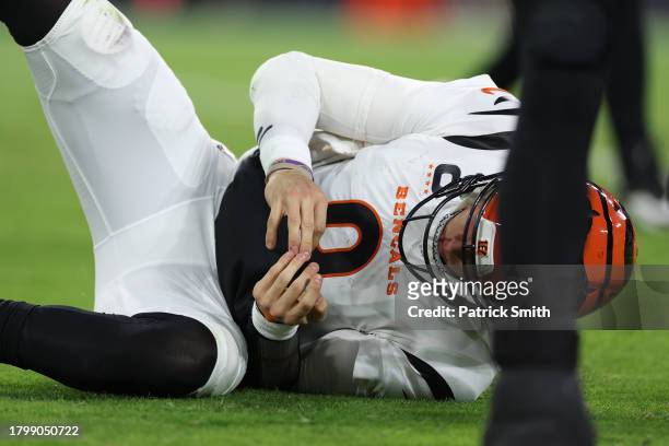 Quarterback Joe Burrow of the Cincinnati Bengals looks at his hand after throwing a pass in front of Odafe Oweh of the Baltimore Ravens during the...