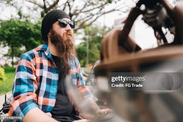 contemplative mid adult man sitting on his motorcycle in the street - emo guy stock pictures, royalty-free photos & images