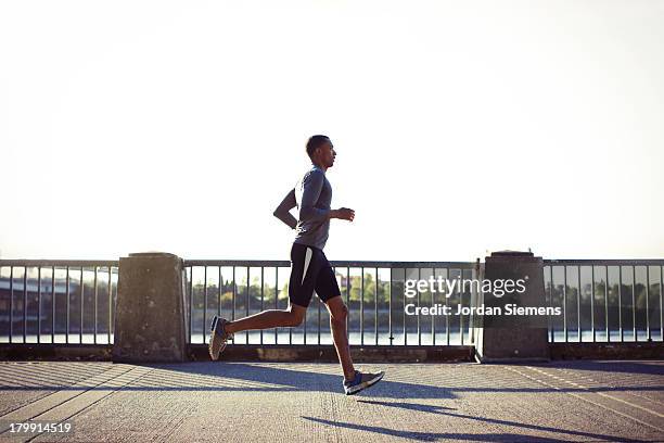 a man running in the city. - running side view stock pictures, royalty-free photos & images