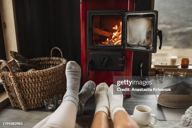 couple in knitted socks near fireplace at home. - cosy socks stock pictures, royalty-free photos & images