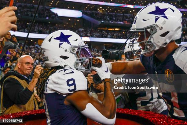 Dallas Cowboys wide receiver KaVontae Turpin jumps into the Salvation Army Kettle as cornerback Eric Scott Jr. Feeds him a turkey leg during the game...