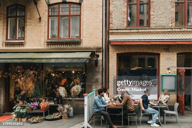 male and female multiracial coworkers having lunch together outside restaurant - gothenburg stock pictures, royalty-free photos & images