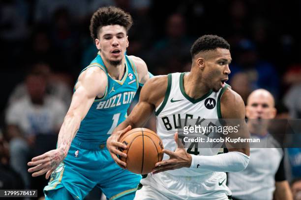 Giannis Antetokounmpo of the Milwaukee Bucks keeps the ball away from LaMelo Ball of the Charlotte Hornets in the third quarter during an NBA...