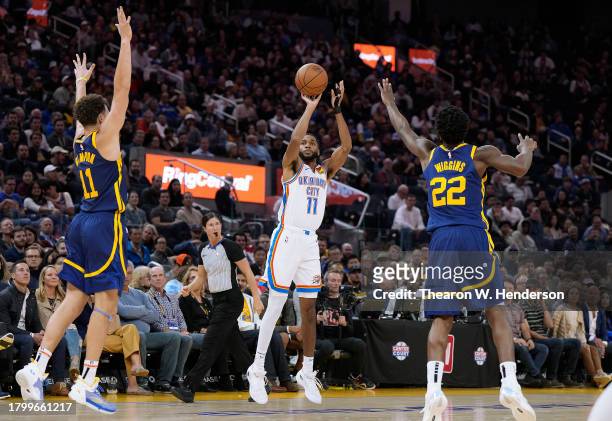 Isaiah Joe of the Oklahoma City Thunder shoots a three-point shot over Andrew Wiggins and Klay Thompson of the Golden State Warriors during the...