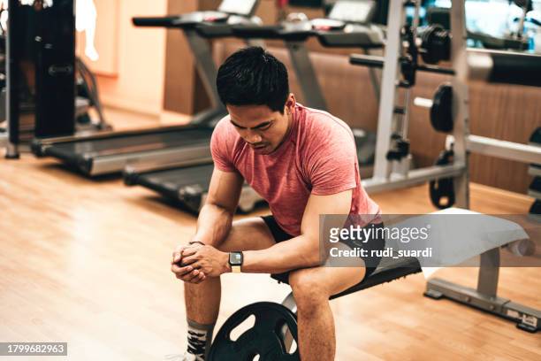 young asian sport men check the sports watches after exercising. - gym resting stock pictures, royalty-free photos & images