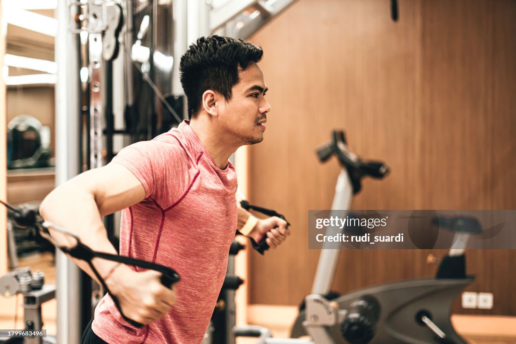 Young man working out on rowing machine in gym