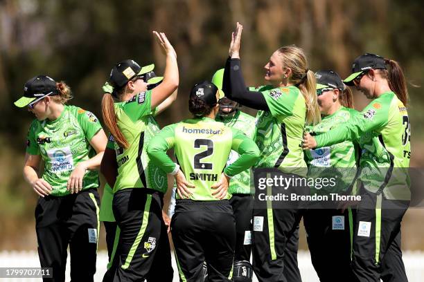 Sammy Jo-Johnson of the Thunder celebrates with team mates after claiming the wicket of Sophie Devine of the Scorchers during the WBBL match between...