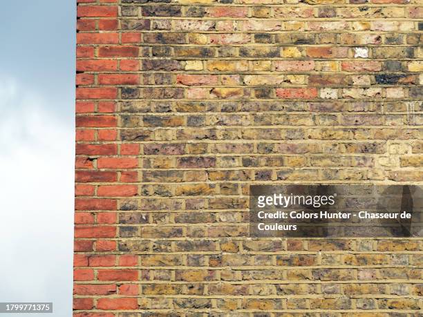 close-up of a wall made of weathered and colored bricks against a background of blue and cloudy sky in london, england, united kingdom - brick wall close up stock pictures, royalty-free photos & images