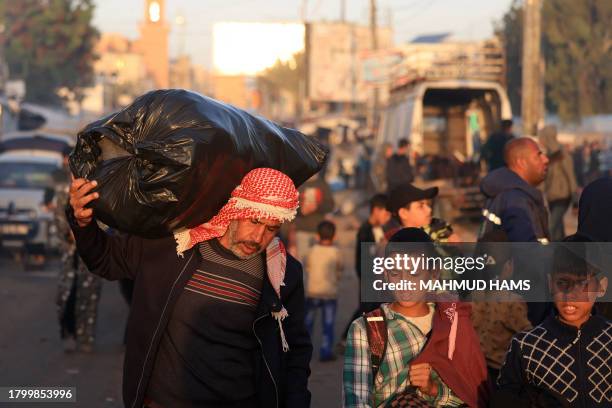 People carry their belongings as Palestinians who had taken refuge in temporary shelters return to their homes in eastern Khan Yunis in the southern...