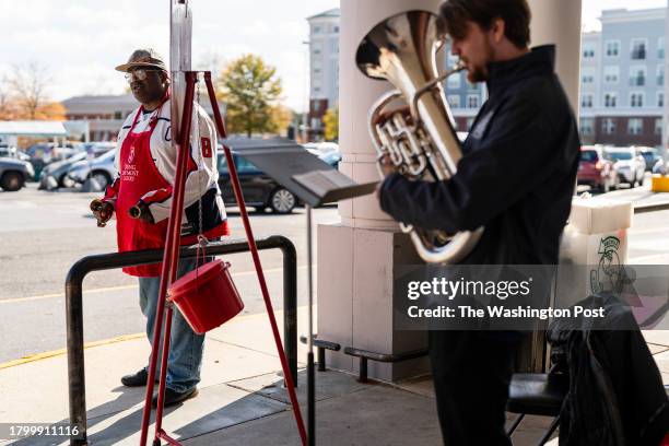 Stuart Goins a bell ringer for the Salvation Army, rings bells to greet shoppers as Anders Ljungholm corps mission associate of the Alexandria, VA...