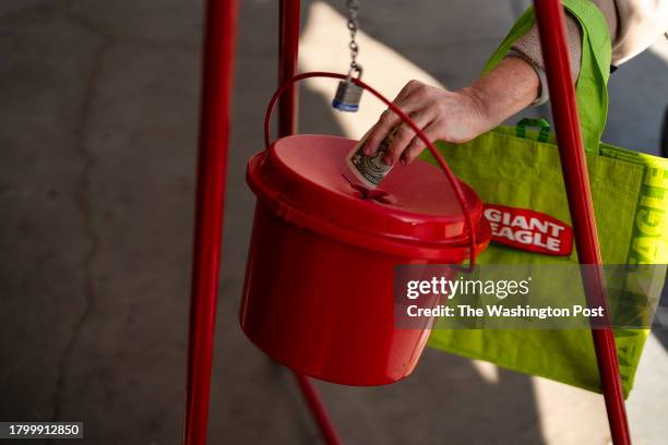 Woman puts money into a Salvation Army red kettle outside of Giant Supermarket in Alexandria, Virginia on November 22, 2023. As cash donations...