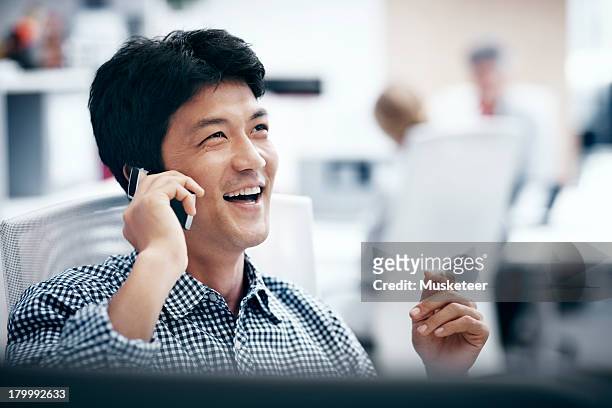smiling businessman talking on a cell phone - content japanese ethnicity stock pictures, royalty-free photos & images
