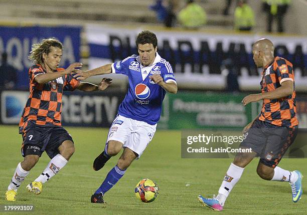 David Ramirez of Millonarios struggles for the ball with Diego Chica and Edwin Movil of Boyaca Chico during a match between Millonarios and Boyaca...