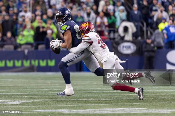 Noah Fant of the Seattle Seahawks is tackled by Percy Butler of the Washington Commanders during the second half at Lumen Field on November 12, 2023...