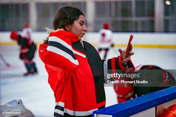 women's ice hockey offensive player applies makeup by looking at phone screen - hockey player on ice stock pictures, royalty-free photos & images