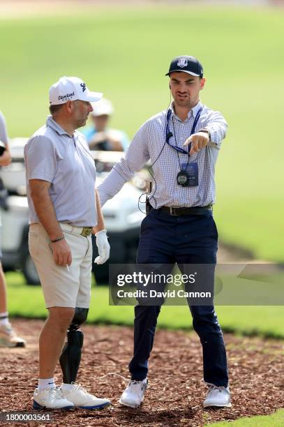 Mike Browne of England gets a ruling from G4D Tour referee Richard Warren of England as he prepares to play his fourth shot on the 18th hole during...