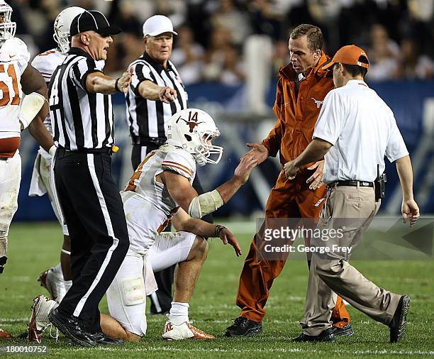 Quarterback David Ash of the Texas Longhorns is assisted by trainers after he was hurt on a play against the BYU Cougars during the second half of an...