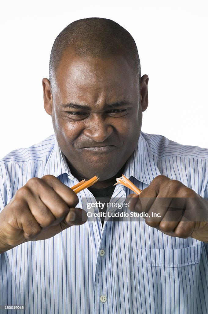 Angry man breaking a pencil