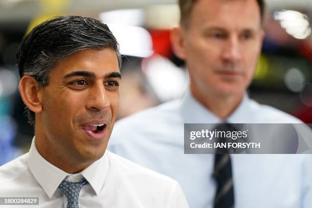 Britain's Prime Minister Rishi Sunak and Britain's Chancellor of the Exchequer Jeremy Hunt react during a visit to the Nissan production plant in...