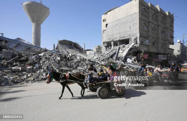 Donkeys carry families to their homes as thousands of displaced Palestinians go to check on their homes as the 4-day humanitarian pause begins for...