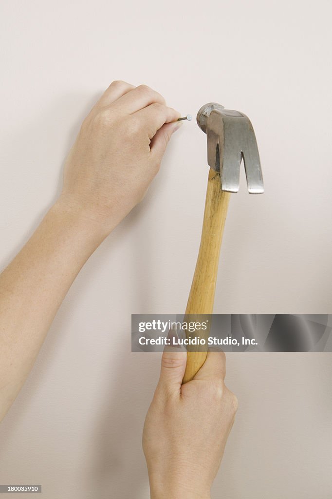 Woman Hammering A Nail Into A Wall High-Res Stock Photo - Getty Images