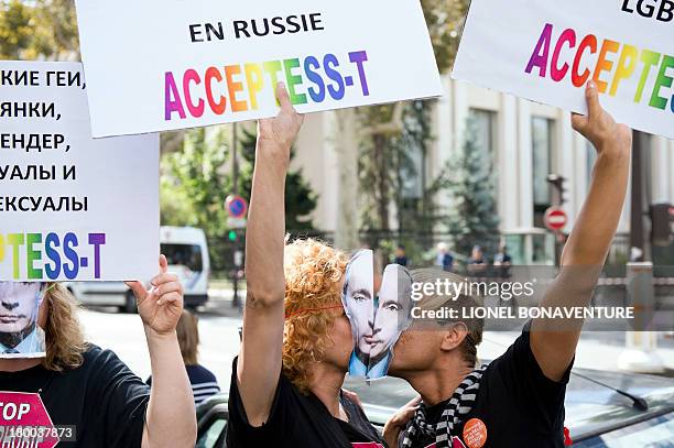 Demonstrators wearing masks depicting Russian President Vladimir Putin kiss and hold placards as they take part in a rally in front of the Russian...