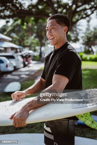 junger mann wächst surfbrett in öffentlichem park - hawaiianischer-abstammung stock-fotos und bilder