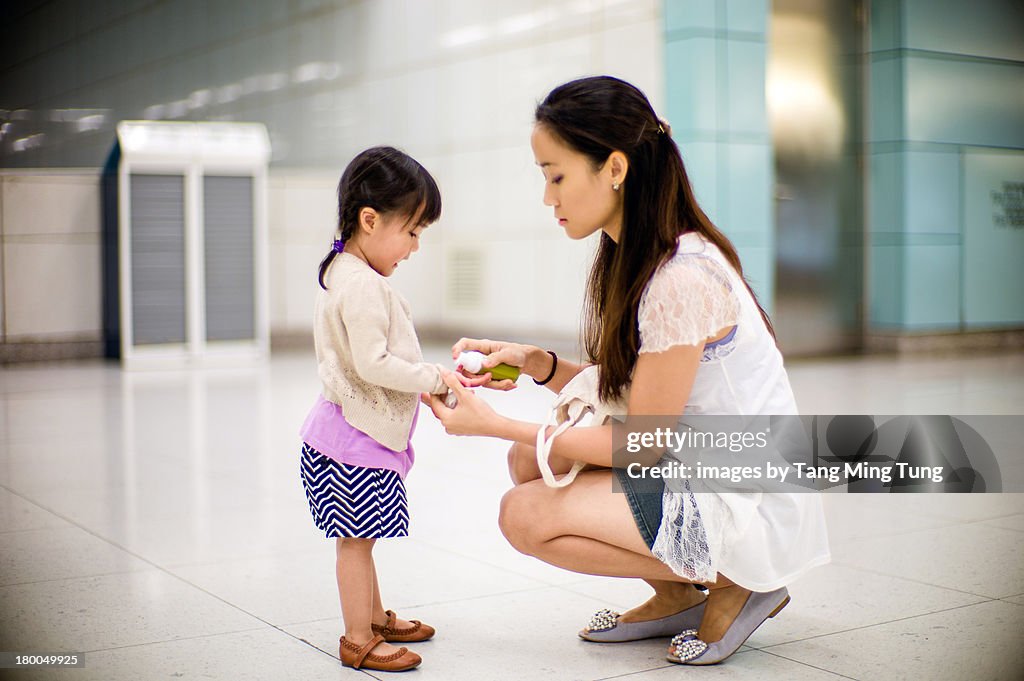 Young mom cleaning toddler's hand with sanitizers
