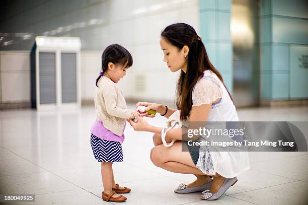 Young Mom Cleaning Toddlers Hand With Sanitizers, Foto de stock