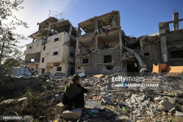 Graphic content / TOPSHOT - A Palestinian woman sits amid the destruction as people returning to Khan Yunis inspect the damage to their homes from...