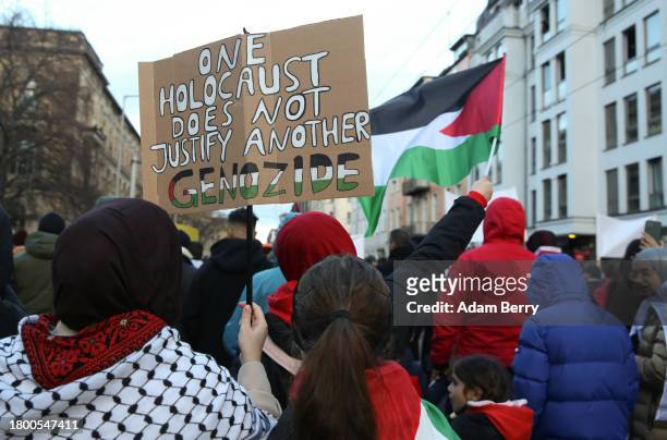 Protester holds a sign reading "One Holocaust Does Not Justify Another Genocide," with the last word written in German, as she attends a...