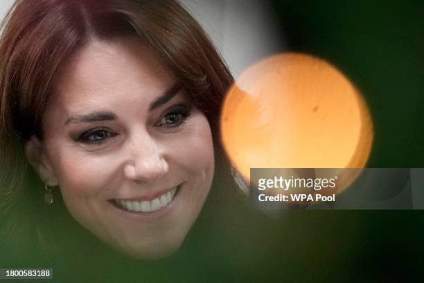 Catherine, Princess of Wales seen behind Christmas tree decorations as she talks to people during her visit to Sebby's Corner on November 24, 2023 in...